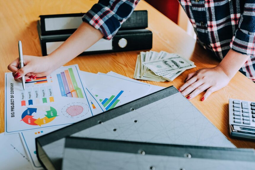 Wysoki kąt widoku kobiety analizującej wykresy według papieru walutowego na stole