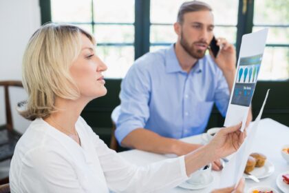 Żeński wykonawczy patrzeje dokument podczas gdy kolega opowiada na telefonie komórkowym